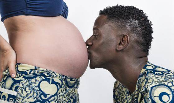 un père embrassant le ventre de sa femme enceinte
